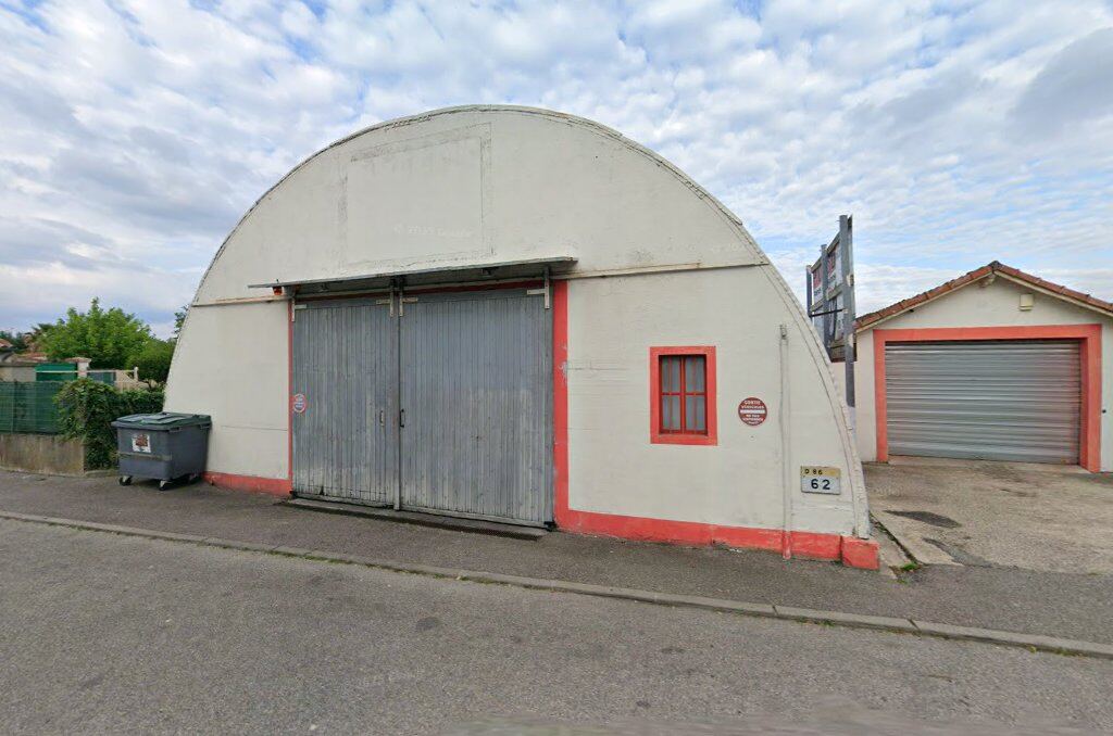 Façade de MECA PNEUS 86 : hangar blanc en arche, grandes portes en tôle grise, plinthe et fenêtre rouges, plaque D 86 · 62, avenue de Provence à Saint-Georges-les-Bains